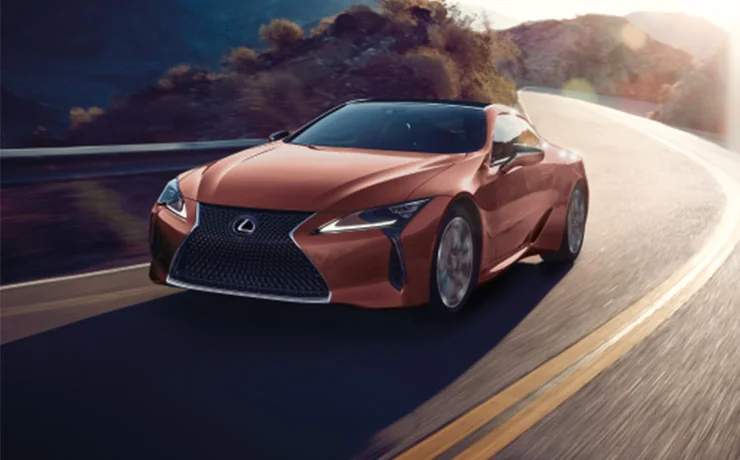 Orange Lexus driving on road by lake in motion