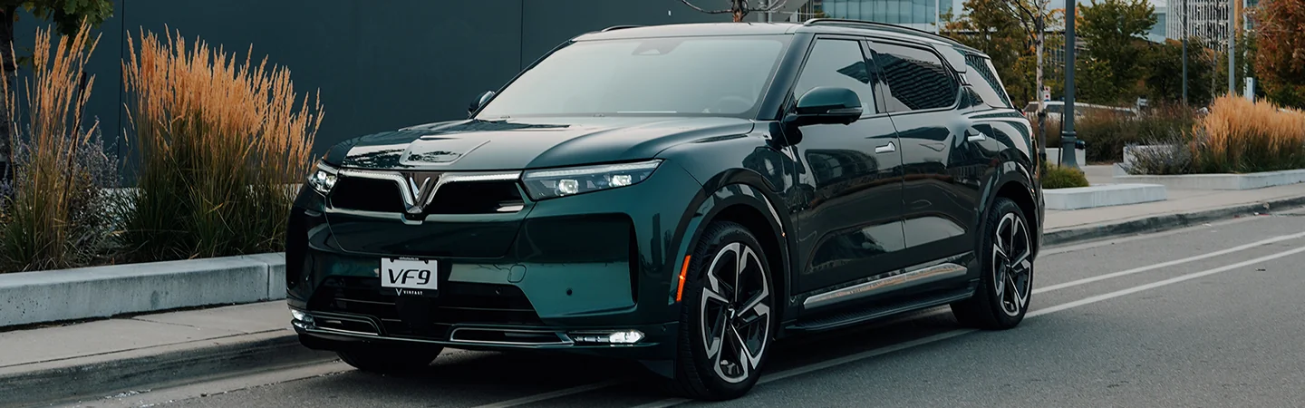 Front side view of a parked green 2025 VinFast VF 9 in the city