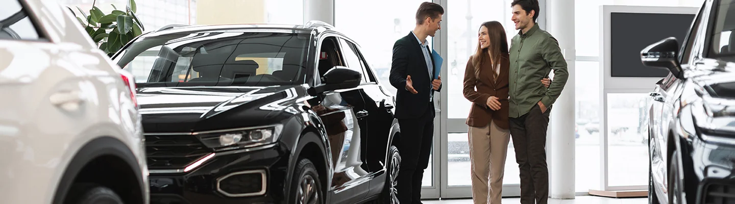 two people discussing car purchase in dealership with another person