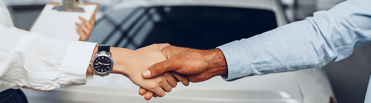 hands shaking with car in background