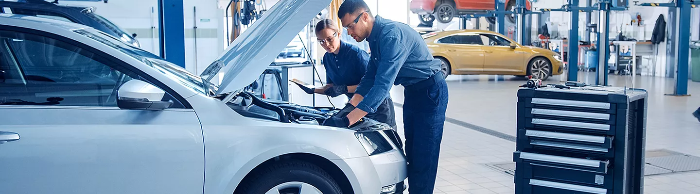 Two mechanics working on a car under the hood