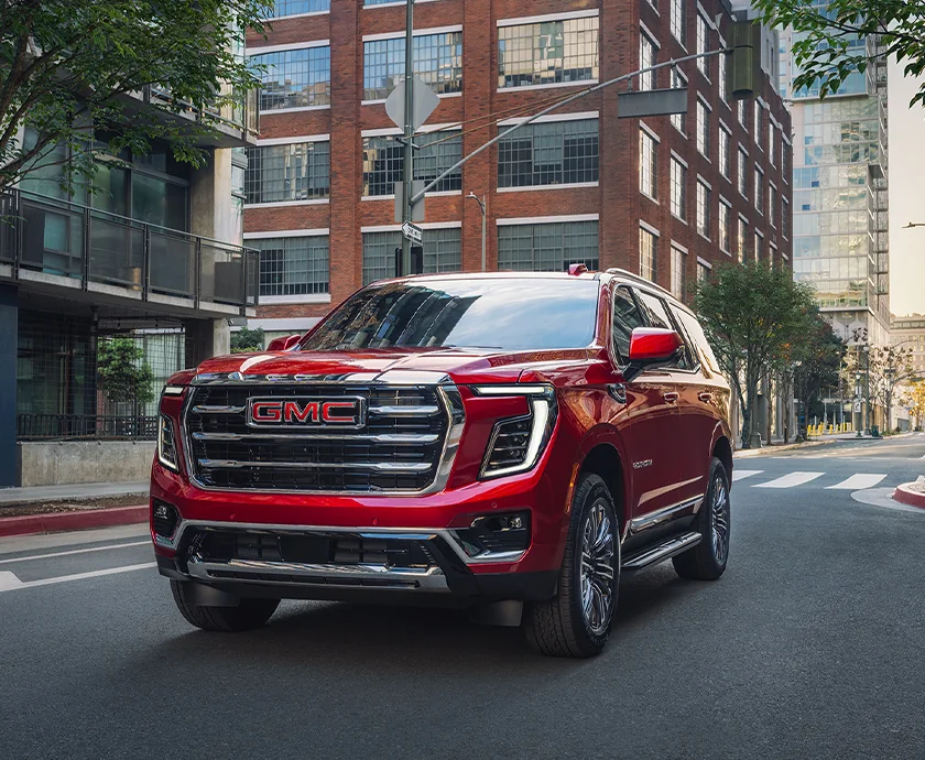 Front view of a red 2026 GMC Yukon driving in the city