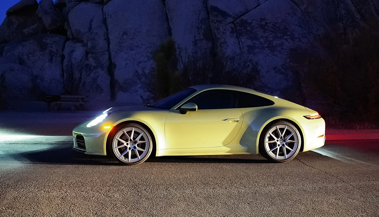 Side view of a parked yellow 911 Carrera at night