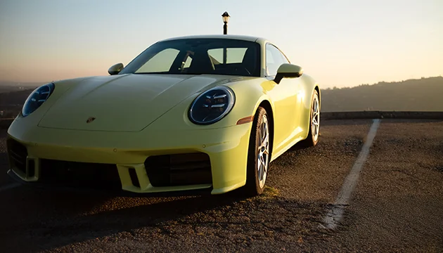 Front view of parked yellow 911 Carrera in the dirt