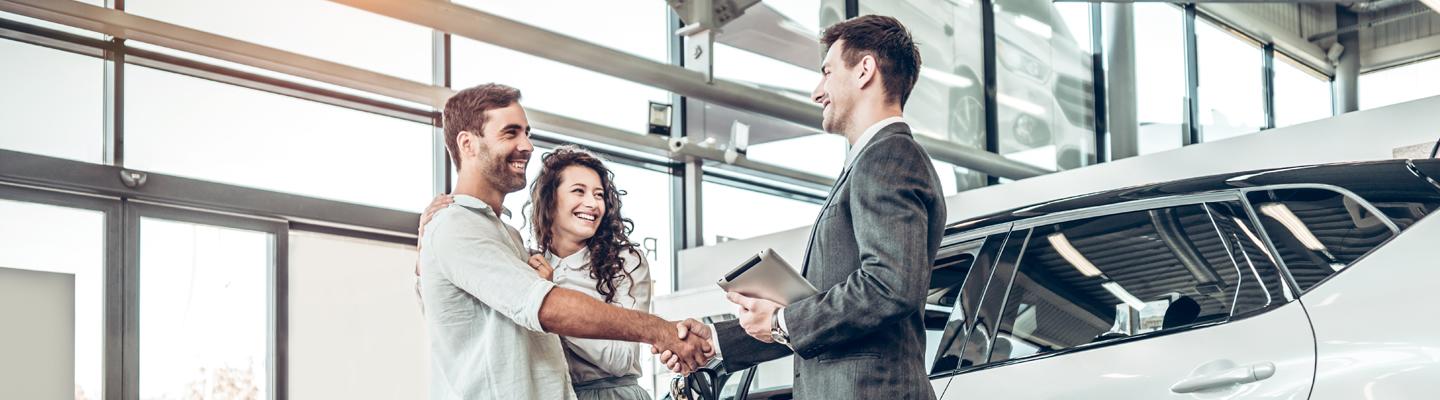 Sales person helping customers out with a used car