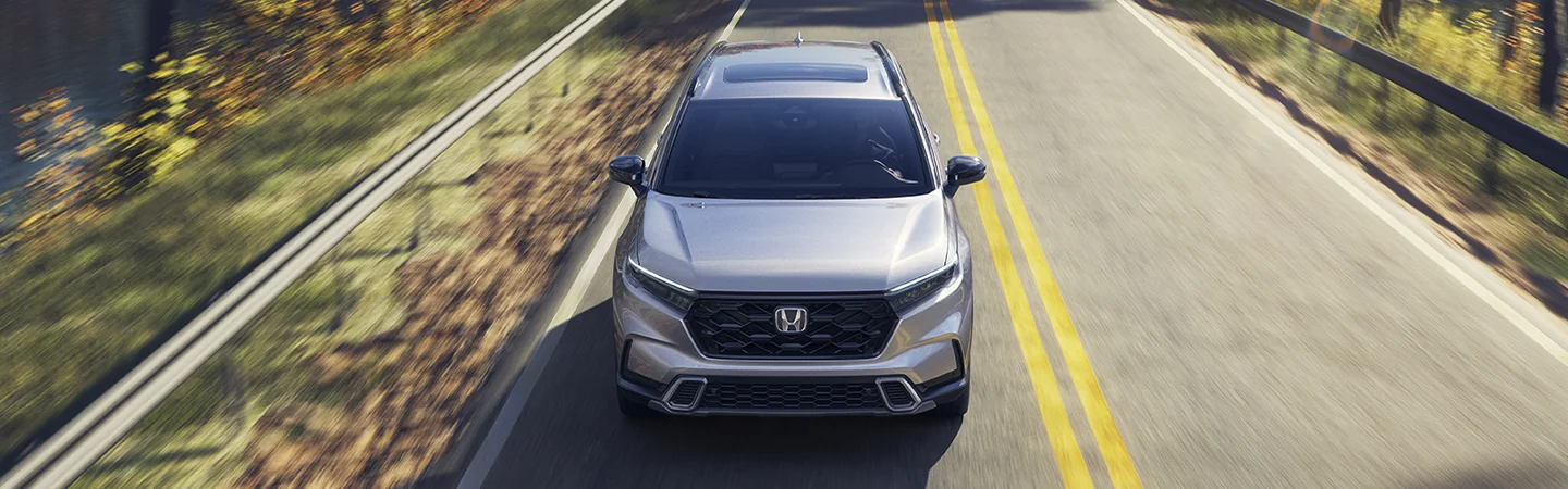 Front top view of a gray 2026 Honda CR-V Hybrid driving on a road