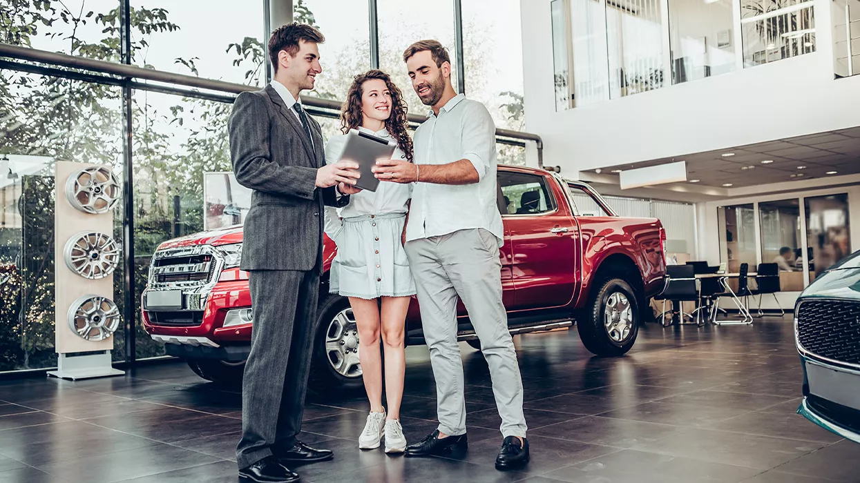 A car salesman talking with a couple in a car dealership