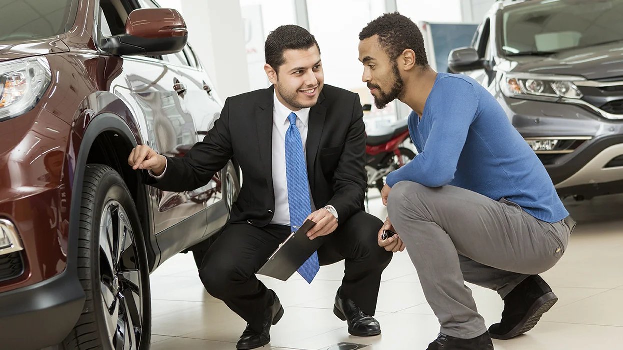 car salesperson speaking with customer in showroom