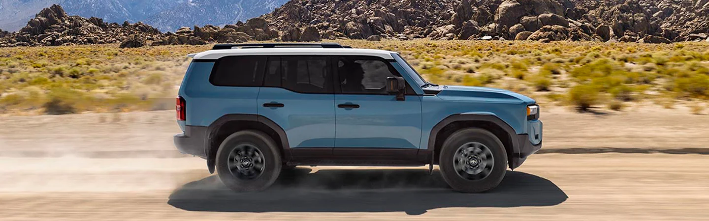 Blue 2025 Toyota Land Cruiser driving through a mountainous area
