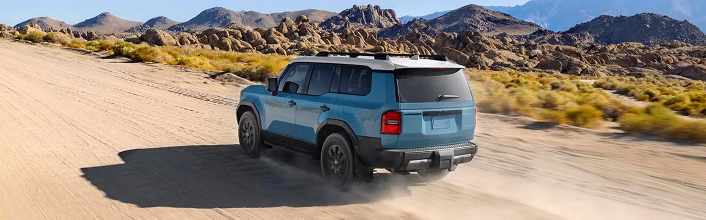 Blue 2025 Toyota Land Cruiser driving through a mountainous area