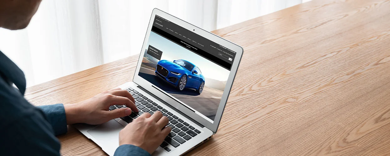 someone on laptop on the web site for Jaguar Ocala shopping for a great financed deal on a new car