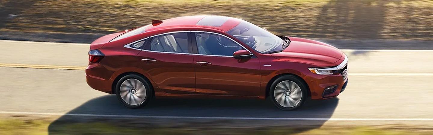 A red 2022 Honda Insight Hybrid drigin on the road
