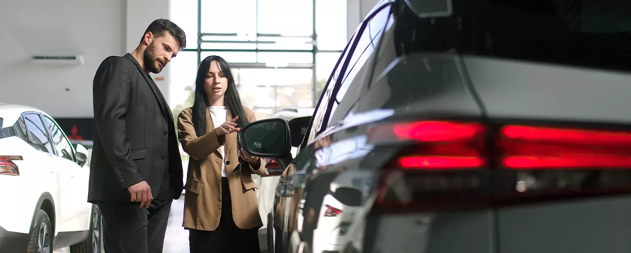 Two people loking at a new subaru car in a dealership
