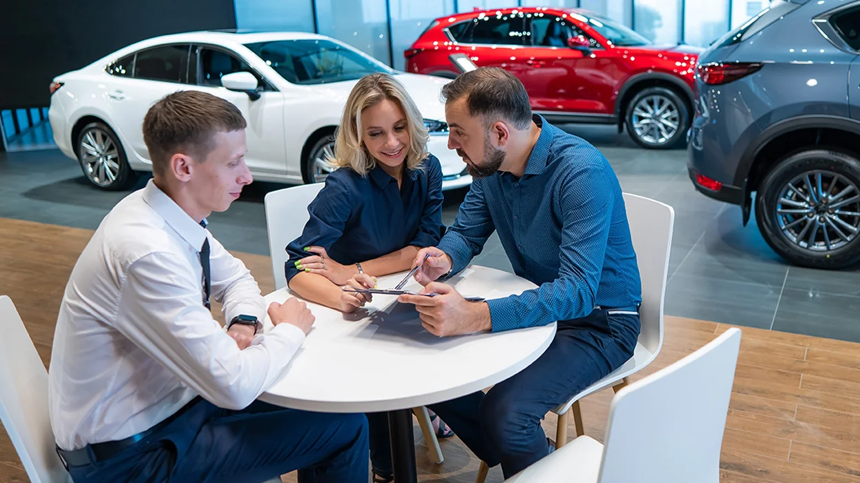 a couple speaking with car salesperson about car lease