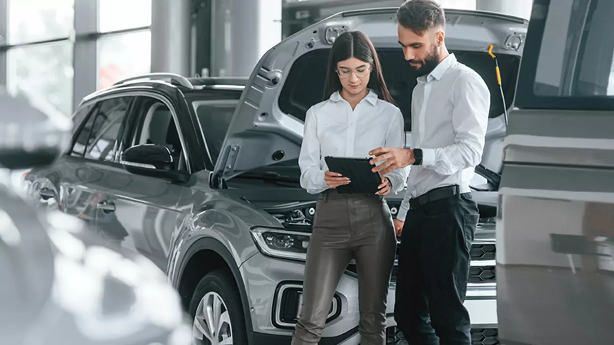 A man and woman examining a car in a modern showroom, showcasing their interest in the vehicle.