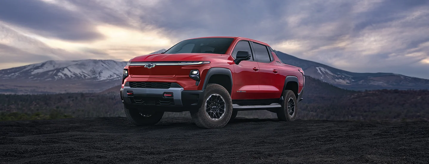 A red 2025 Chevrolet Silverado EV parked with a mountain in the background