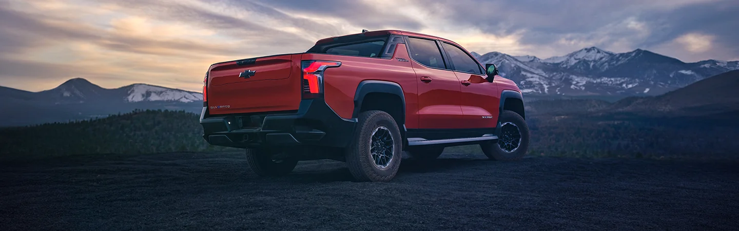 A red 2025 Chevrolet Silverado EV parked with a mountain in the background