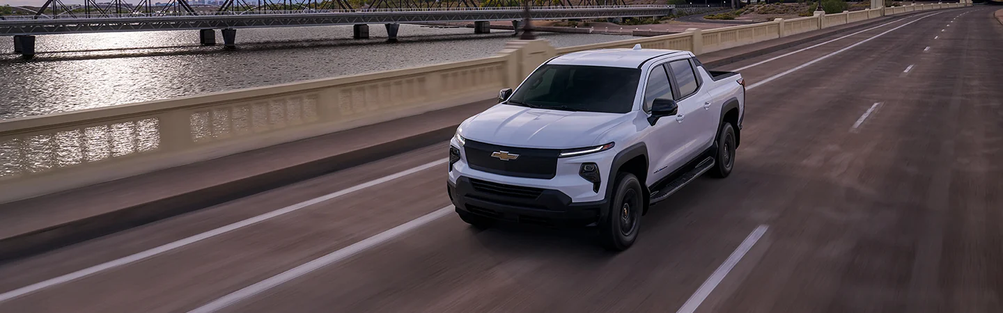 A white 2025 Chevrolet Silverado EV driving over a bridge
