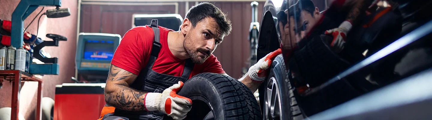 auto mechanic installing tires on car