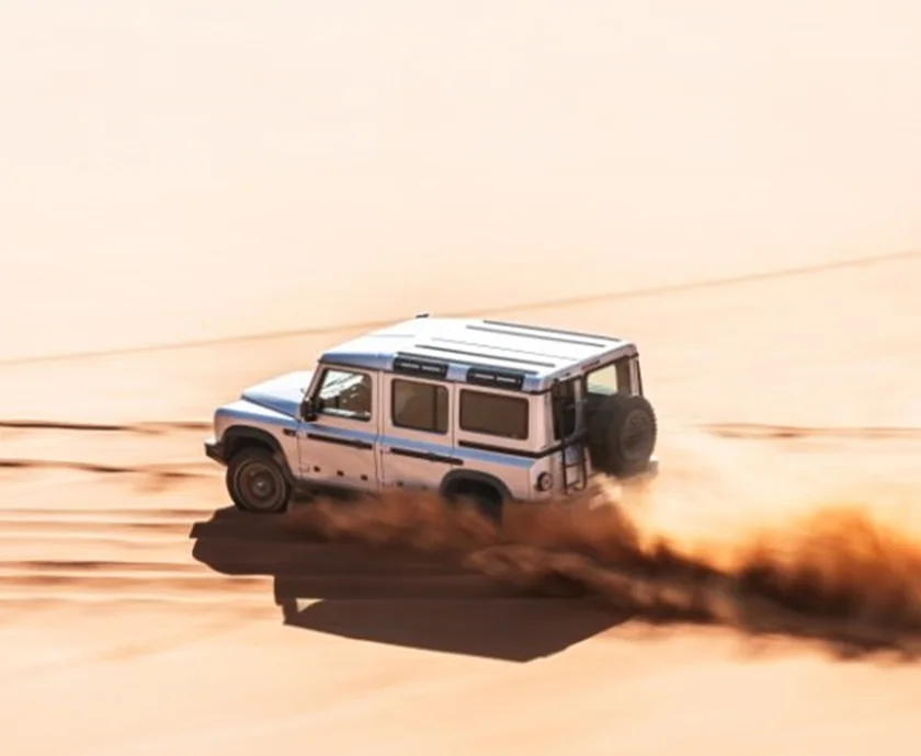 A silver 2026 INEOS Grenadier Trialmaster driving though the desert