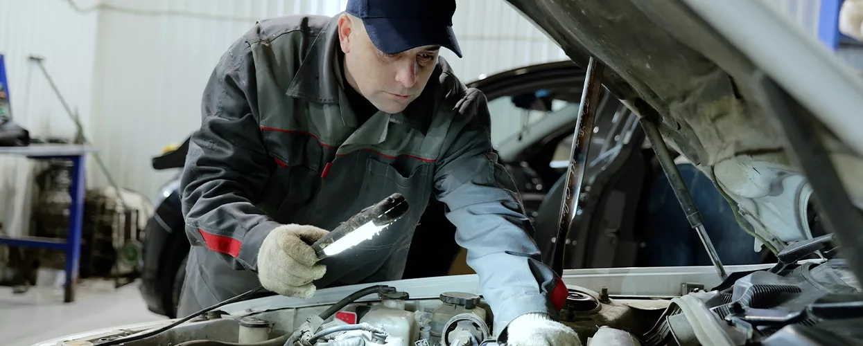 Service mechanic working under the hood of a car