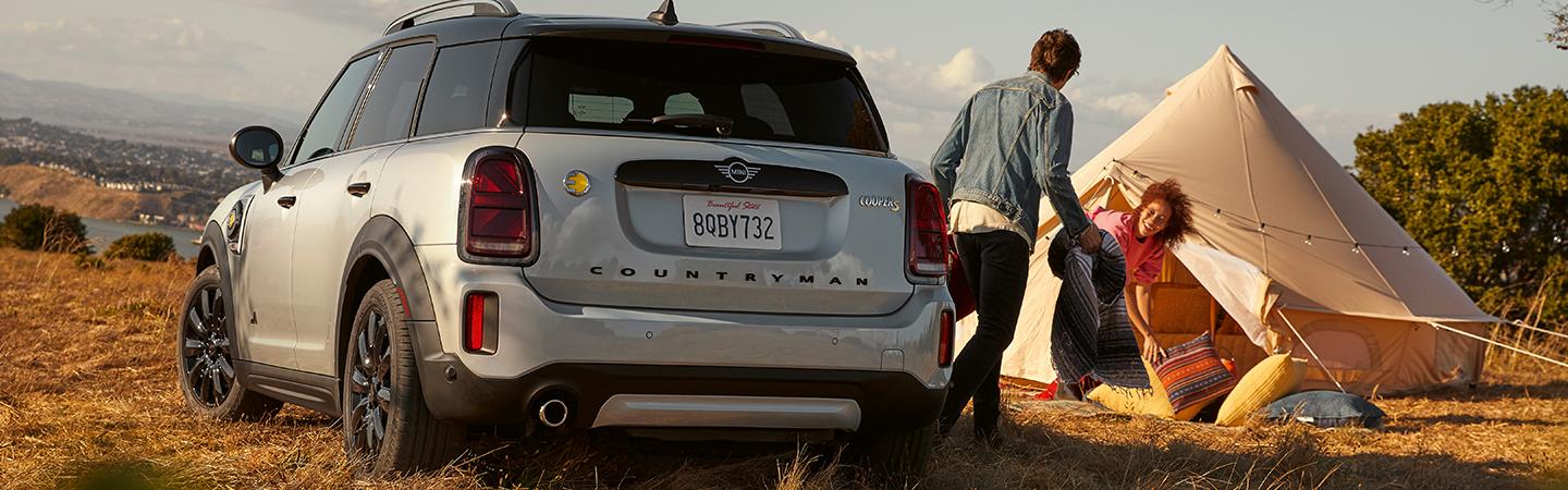Rear view of a silver MINI Countryman parked next to a couple’s campsite