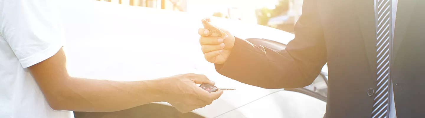 One person handing keys to someone while that person is handing them money