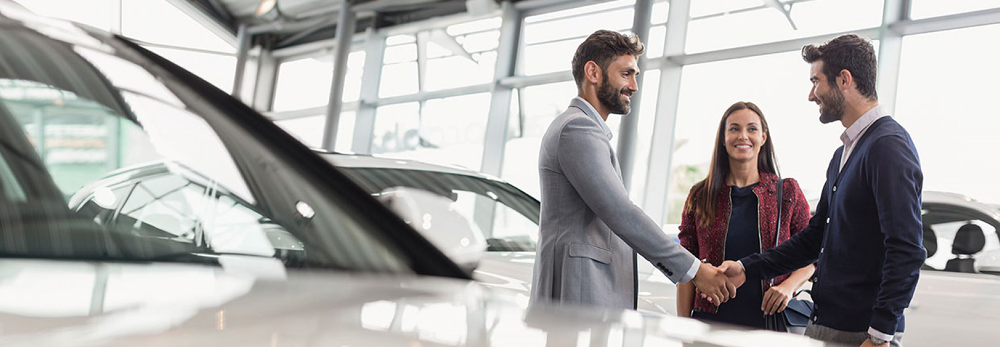 Customer and sales person shaking hands making a deal on a new car