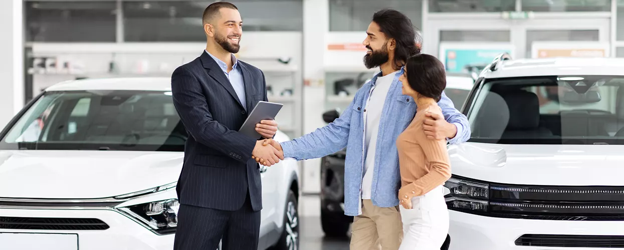 salesman shaking hand of a husband with his wife next to him