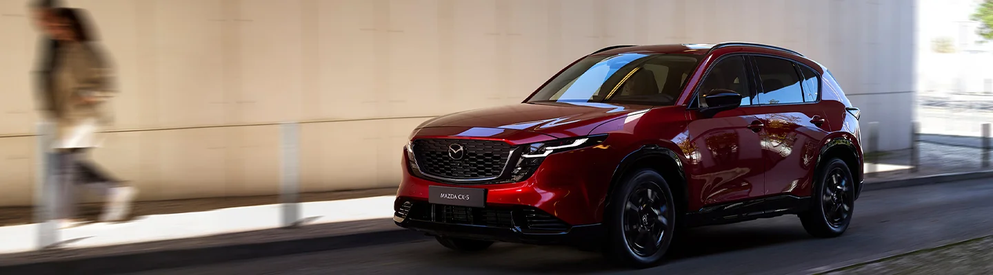 Frotn side view of a red 2026 Mazda CX-5 driving in the city