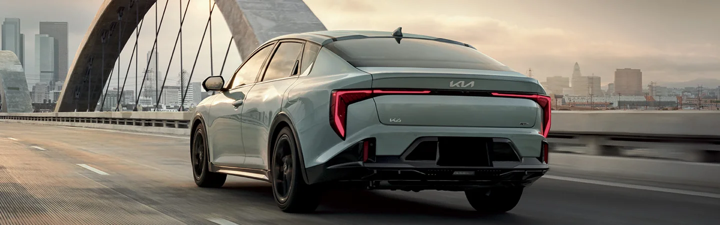 Rear view of a 2025 Kia K4 driving on a bridge in the city