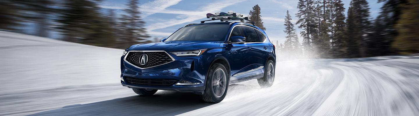 A Blue 2021 Acura MDX in motion through the snow
