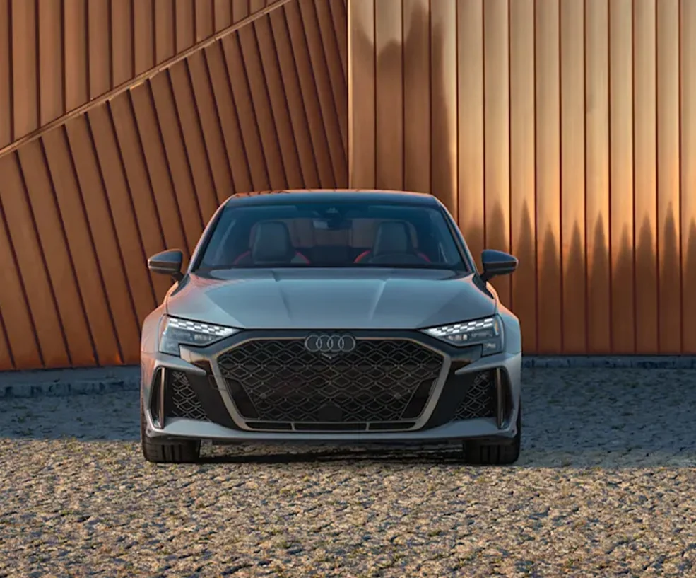 Front view of a parekd gray 2026 Audi RS 3 on a stone drive