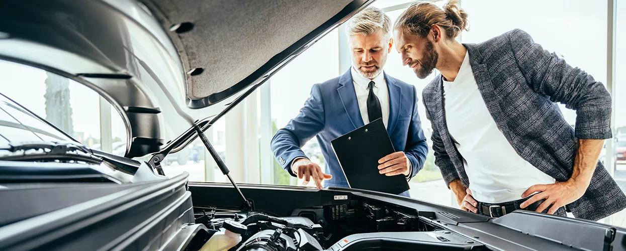 Car salesman showing the engine of a car to a customer