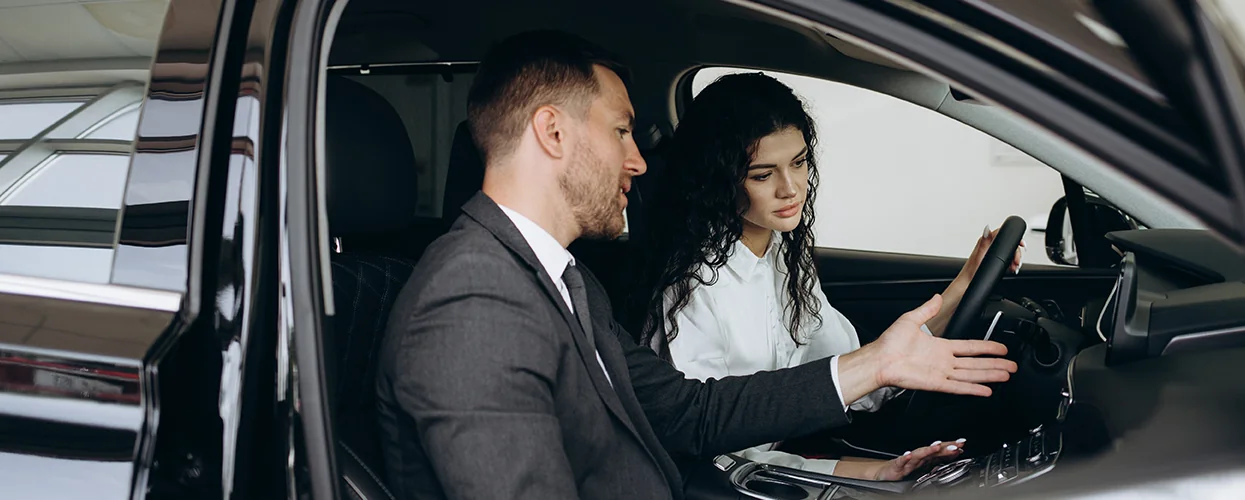 A man and woman engaged in conversation while seated in a Mercedes-Benz.