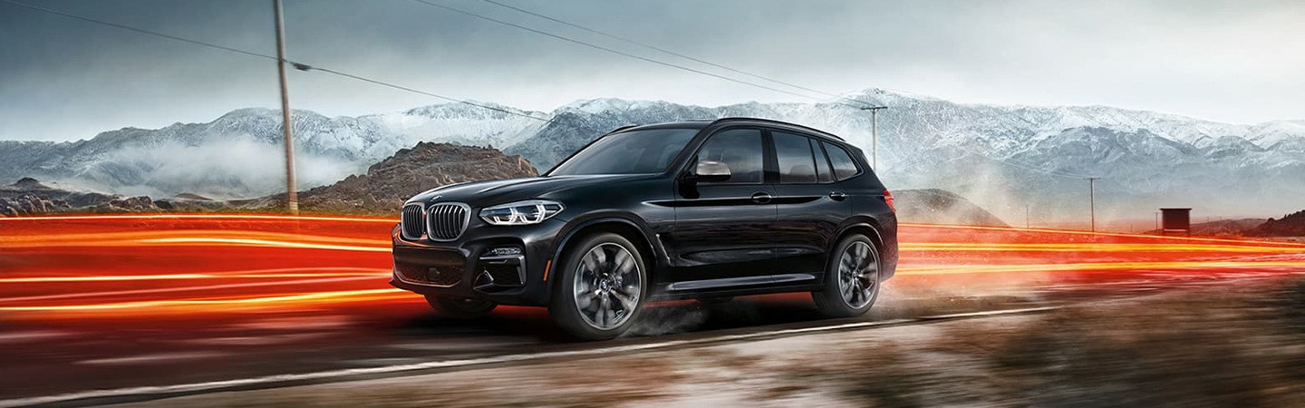 Black 2021 BMW X3 driving by mountains