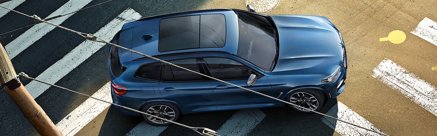 Blue Aerial view of 2021 BMW X3 driving through intersection