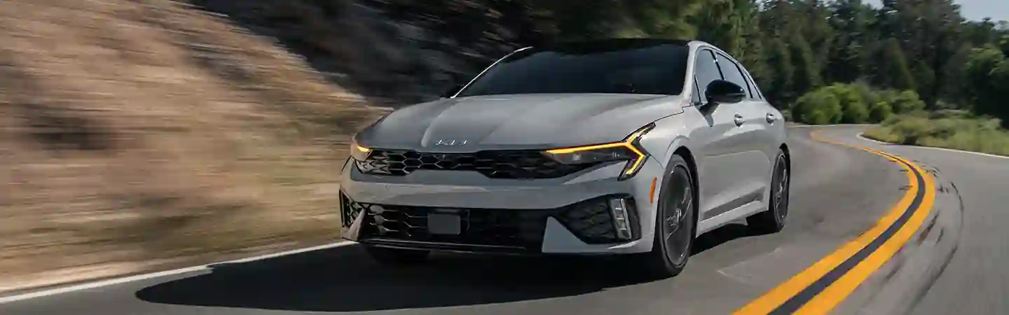 Front view of a 2025 Kia K5 driving on a road