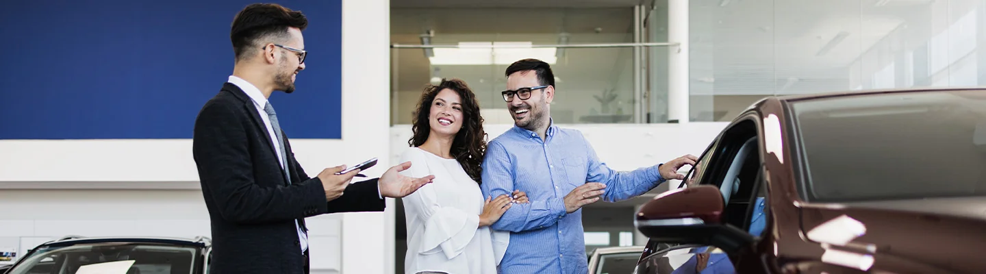 Sales person helping customers look at a new car