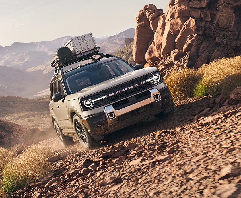 2026 Ford Bronco exterior view hauling gear on top roof rack over dirt rocky road
