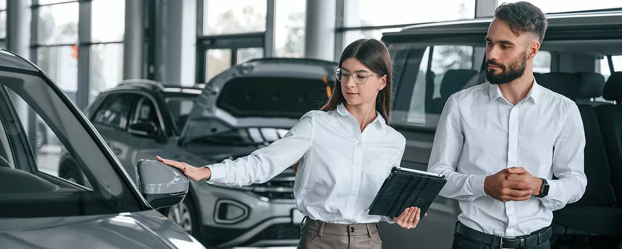 Two people looking at a new ford vehivle in a car dealership