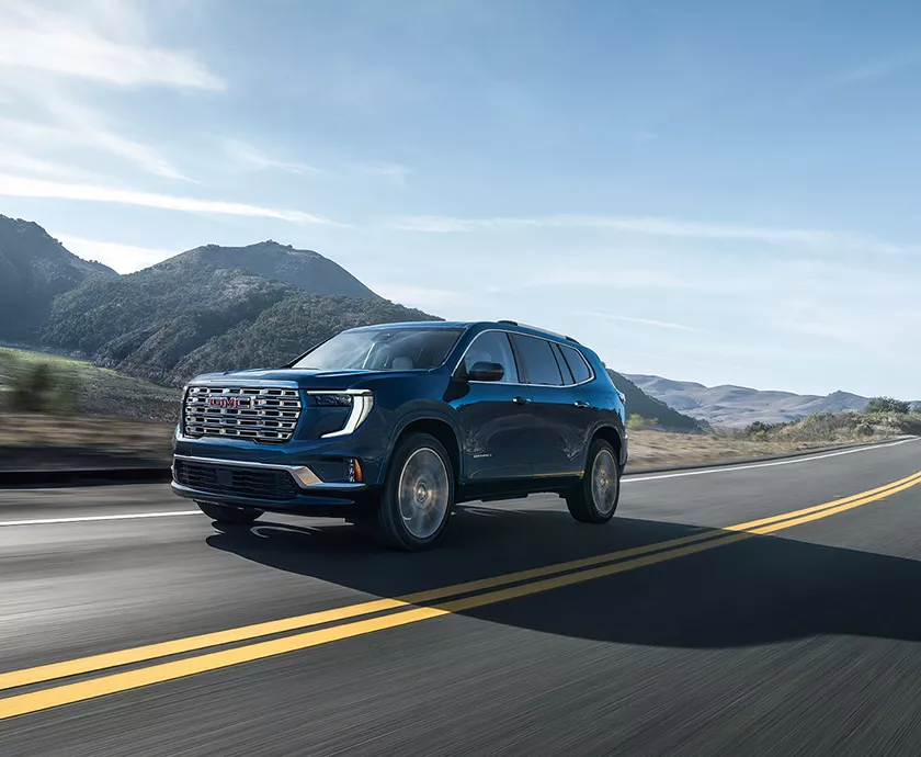 2026 GMC Acadia driving with mountains in the background