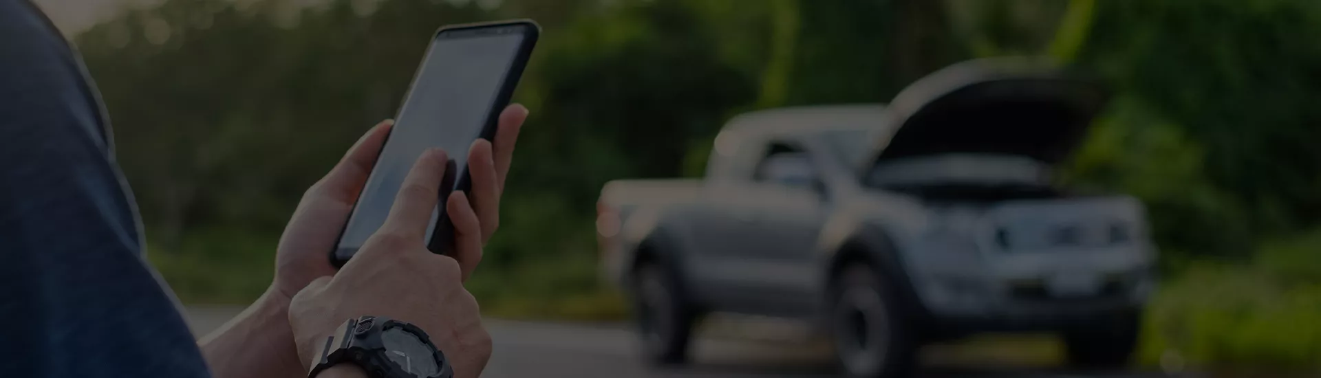Man using his phone with his car in the background