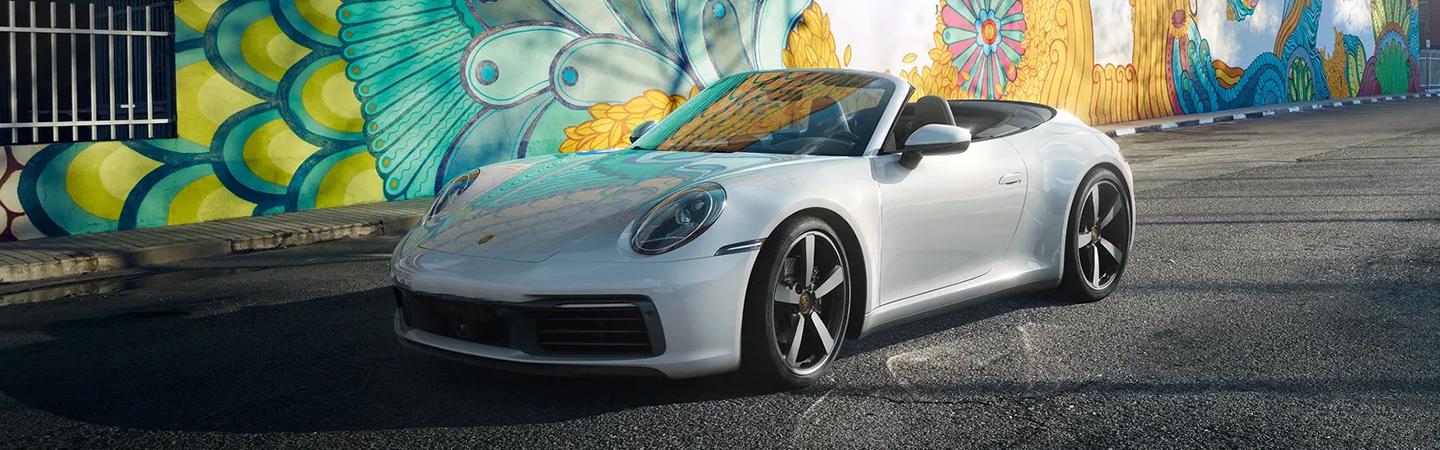 A white 2021 Porsche 911 parked in front of a mural