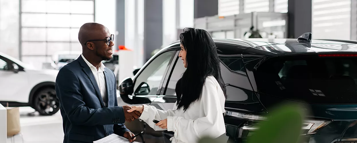 Car salesman handing customers a new set of car keys