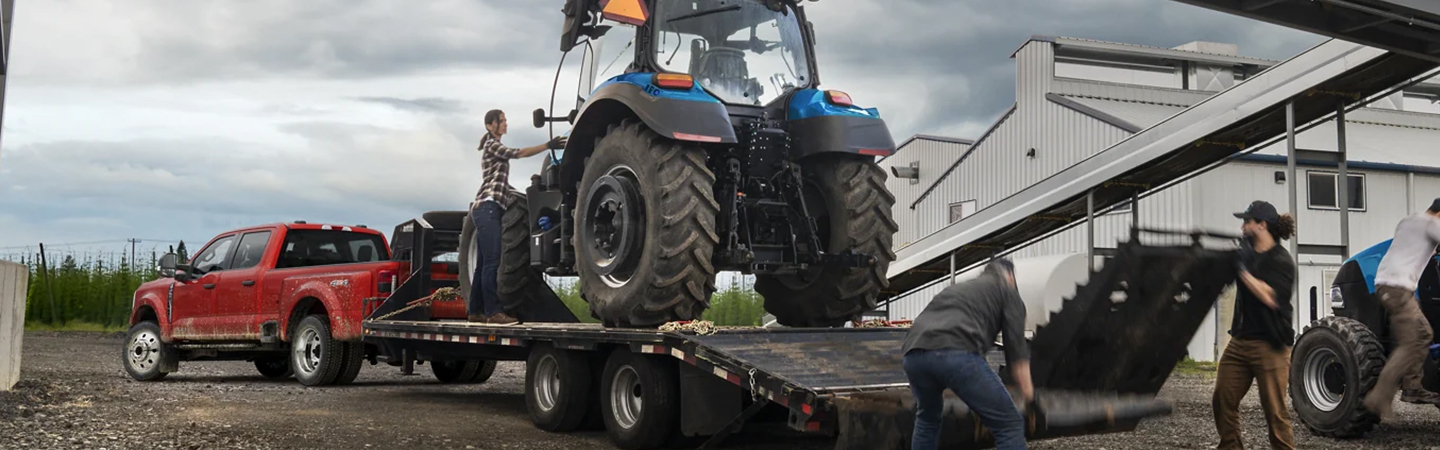 2023 Ford Super Duty parked hauling a trailer with a farm tractor being loaded on to the trailer