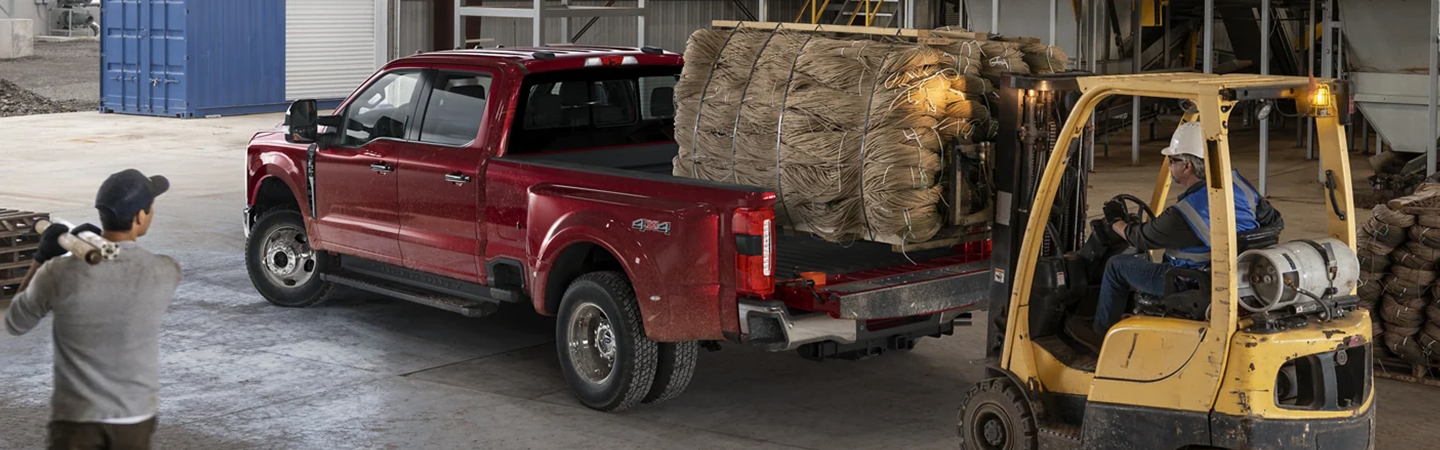 2023 Ford Super Duty parked with a forklift loading material in the truck bed