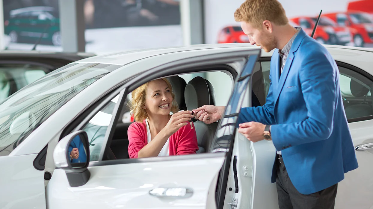 car salesperson with customer sitting in car
