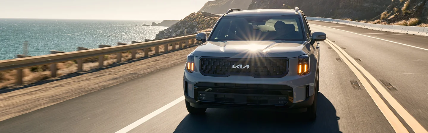 Front view of a 2025 Kia Telluride driving up an ocean side road
