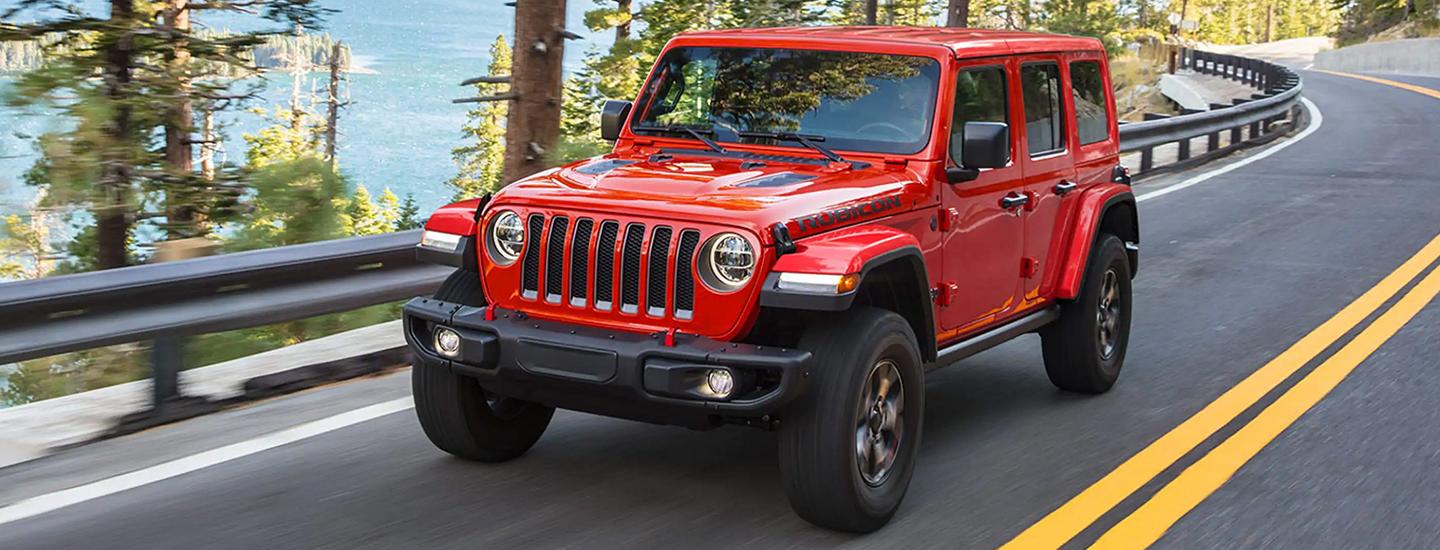 Front view of a red 2021 Jeep Wrangler driving down the road.